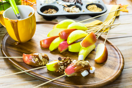 apple slices dipped in caramel and covered with different toppings.